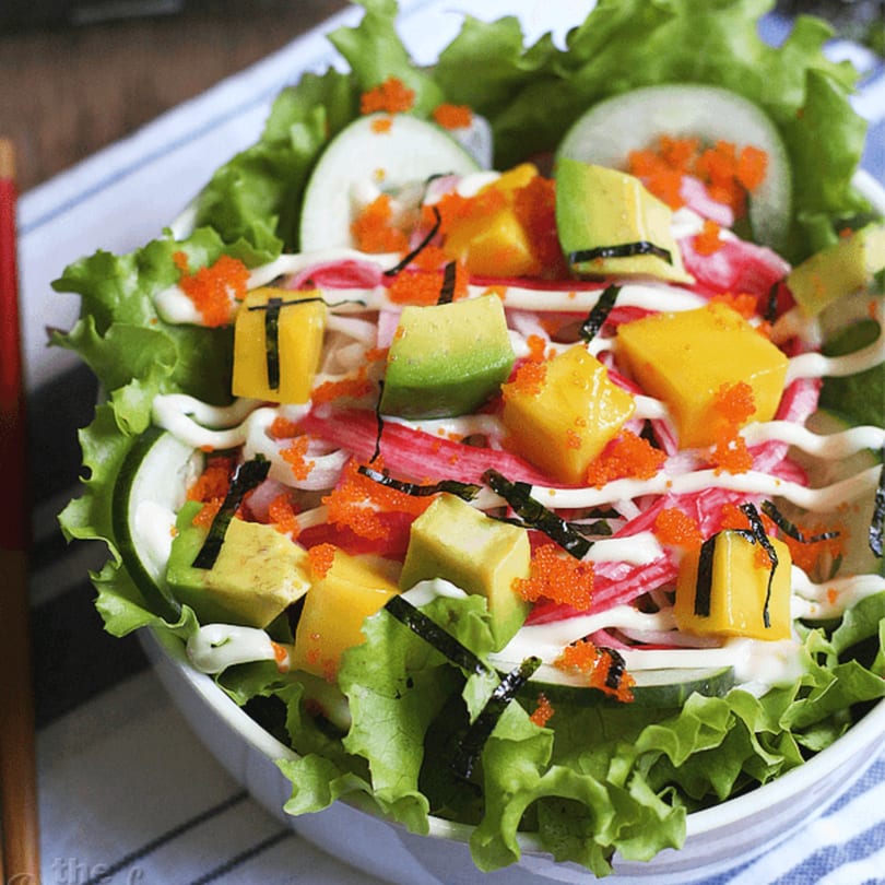 A vibrant Japanese salad with lettuce, crab sticks, avocado, mango, tobiko, and mayonnaise.